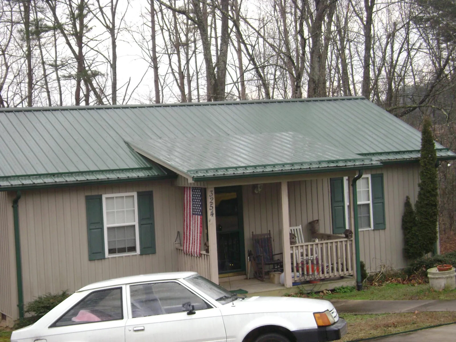 Green metal roof and front porch on a tan sided cottage in Galesburg