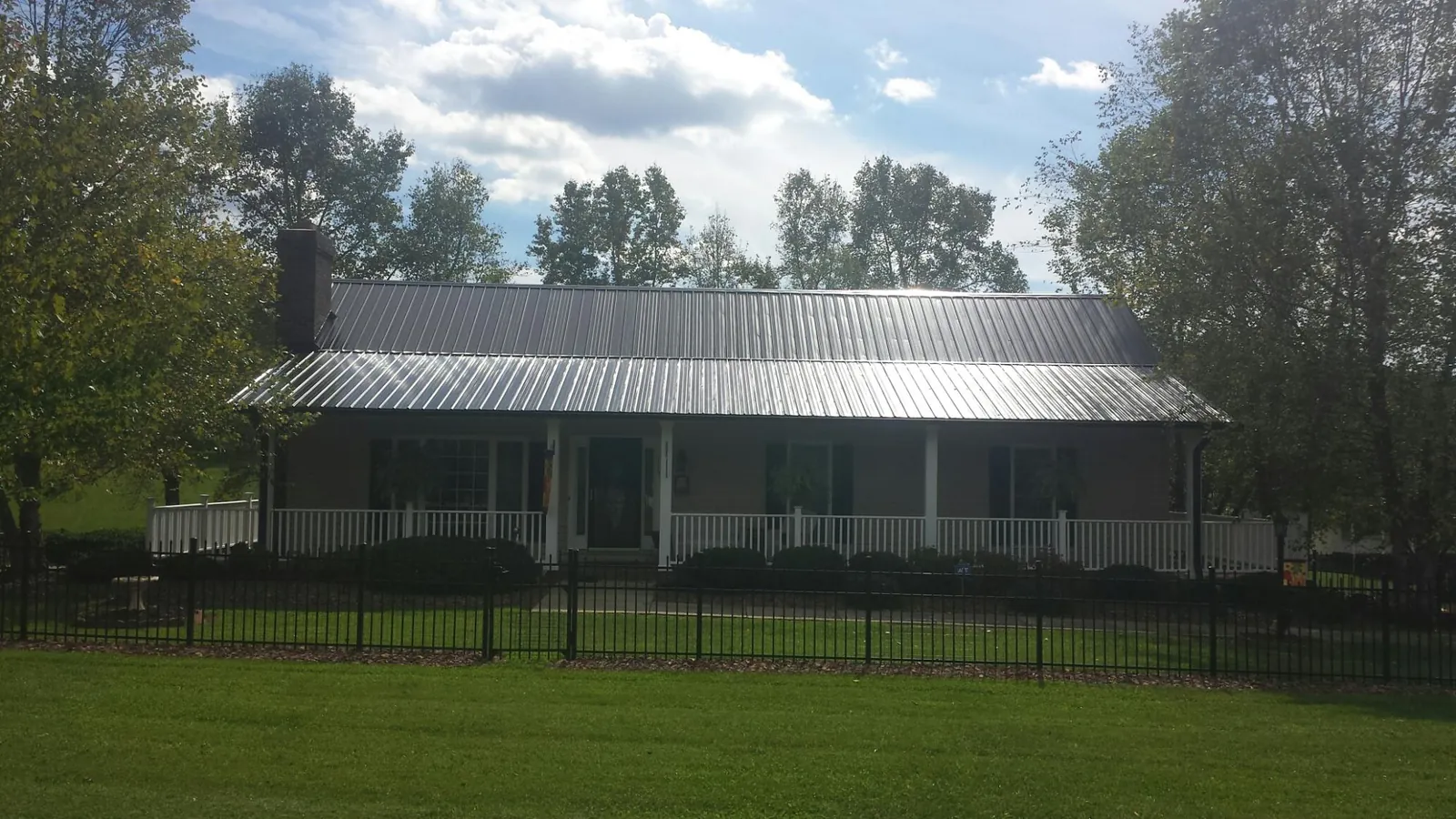 Gray metal roof on a brick ranch with a full width front porch — Gutter Guard Installation work by our crew in Galesburg