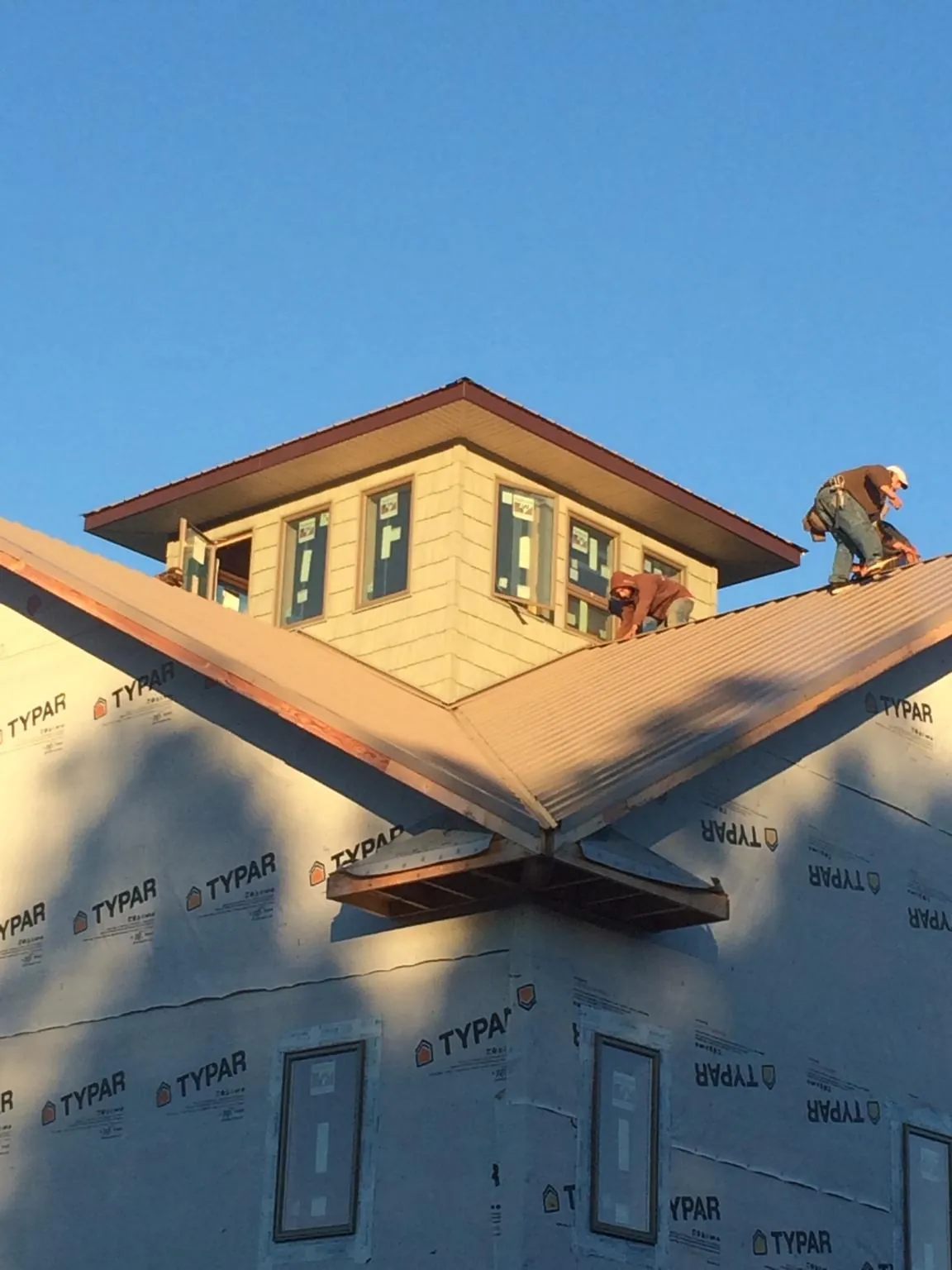 Roofers working around a rooftop cupola on a new metal roof at sunset — Roof Waterproofing in Galesburg by Roofing Brothers